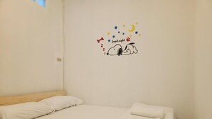A single bed with white bedding and a wall decal featuring Snoopy sleeping under a starry sky with a crescent moon. - Jipu Homestay Ai Yoe Boe Chang (Betong)