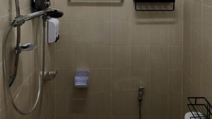 A small, tiled bathroom with a window, a hand dryer, a towel rack, and a toilet paper holder. - Jipu Homestay Ai Yoe Boe Chang (Betong)
