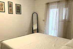 A bedroom with a bed, a mirror, and three framed pictures on the wall.