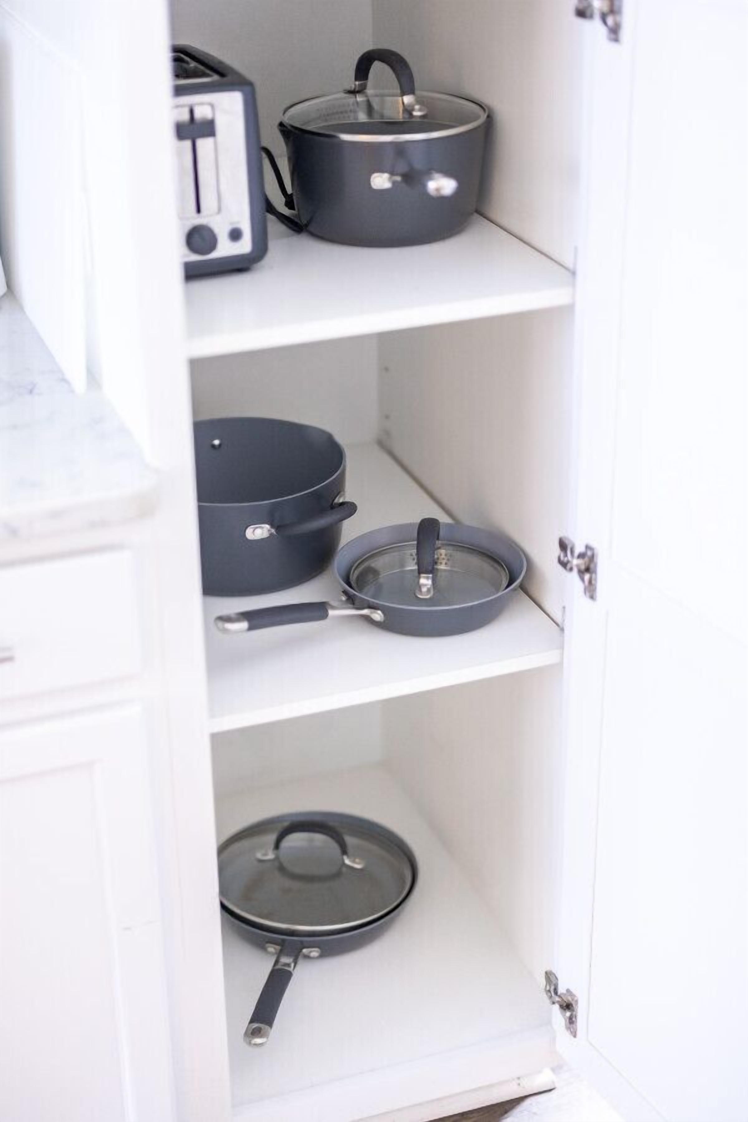 Una cocina con un tostador, una olla, una sartén y una plancha en estantes.