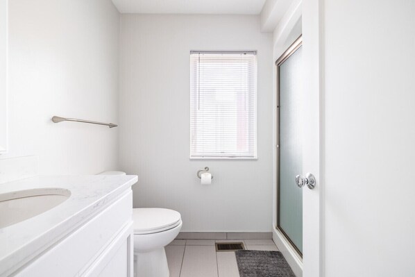 A small, modern bathroom with a toilet, a sink, and a shower.