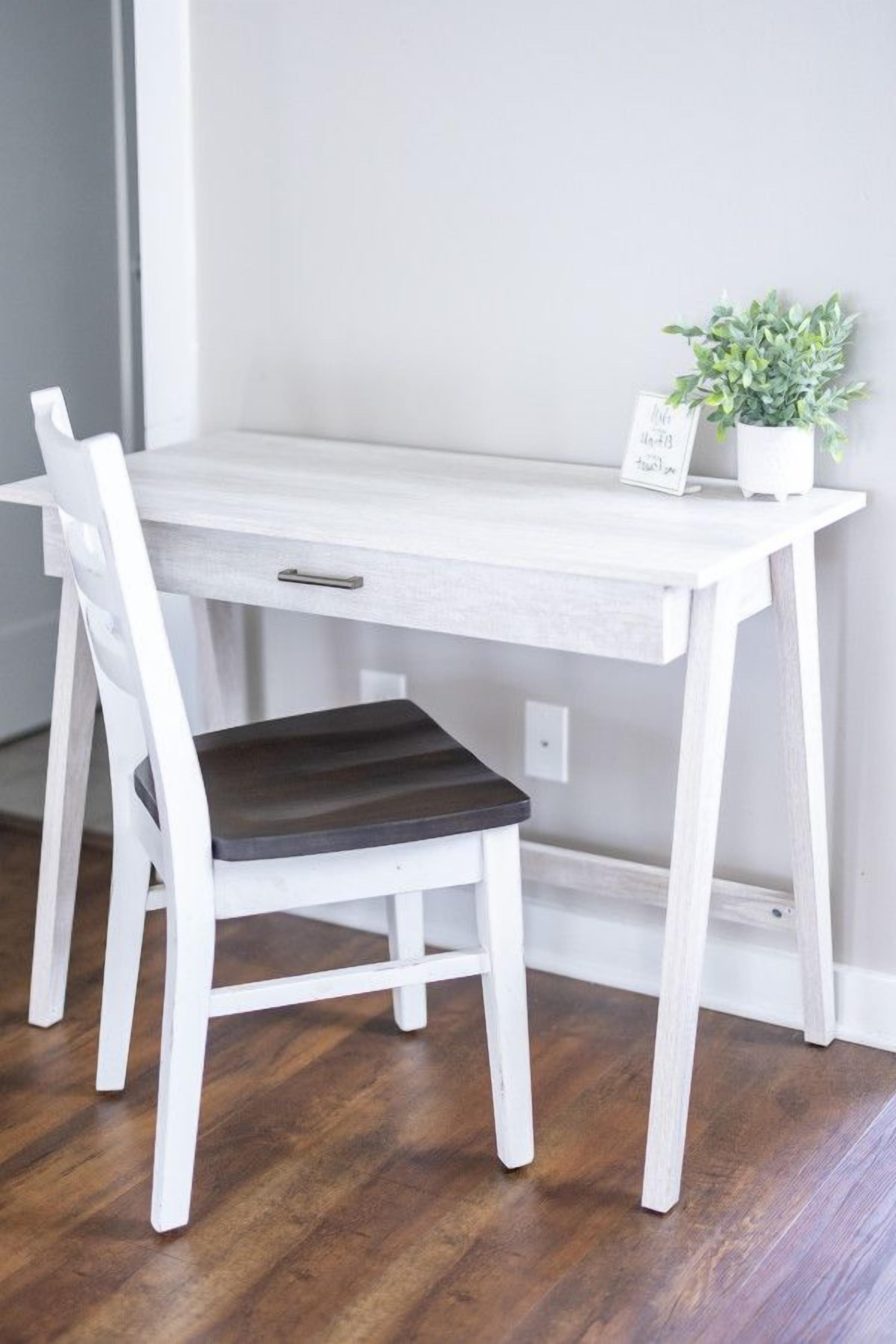 A white wooden desk with a chair, a small potted plant, and a sign on the desk.