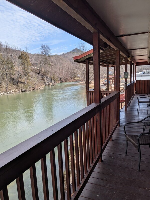 A wooden deck with a railing overlooking a river, with a view of trees and hills in the background. - Damascus Old Mill Inn (Damascus)