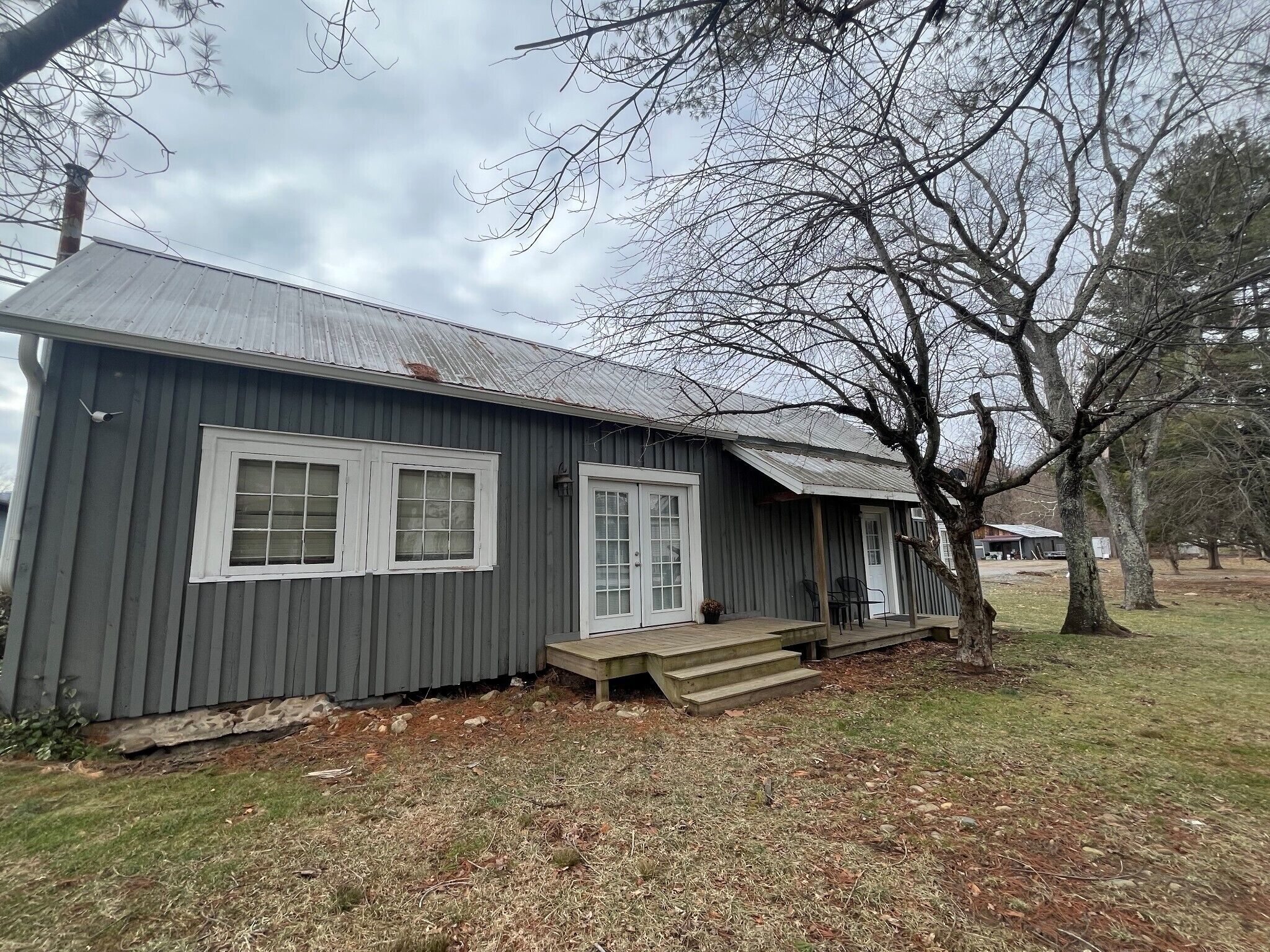 A single-story building with a metal roof, a front porch, and a small set of steps leading to the entrance.