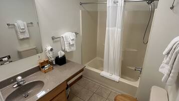 Un baño con lavamanos, espejo, toallero, ducha e inodoro.