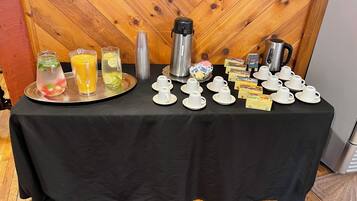 A breakfast buffet table with various beverages and food items.