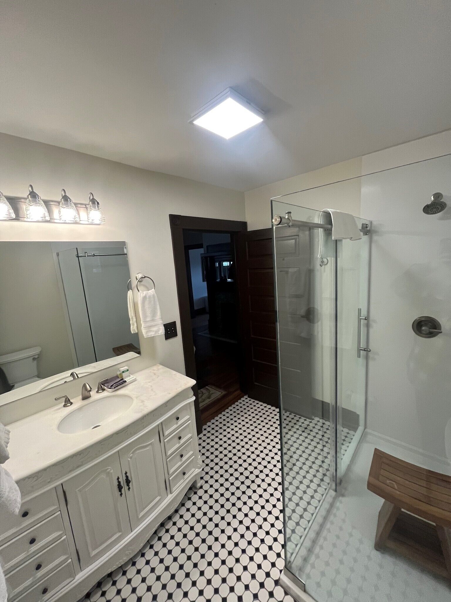 Une salle de bain avec un lavabo blanc, un miroir et une douche en verre.