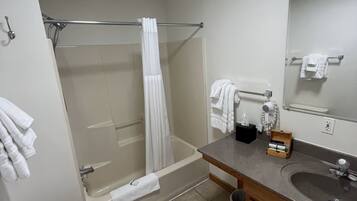 Een badkamer met toilet, douche, bad, wastafel en spiegel.