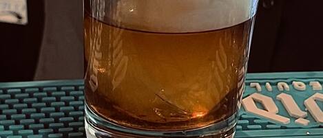 A glass of amber liquid on a teal coaster with a keyboard-like pattern.
