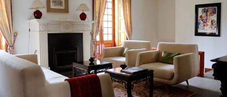 Una sala de estar con chimenea, dos sillones, un sofá, una mesa de centro y una alfombra.