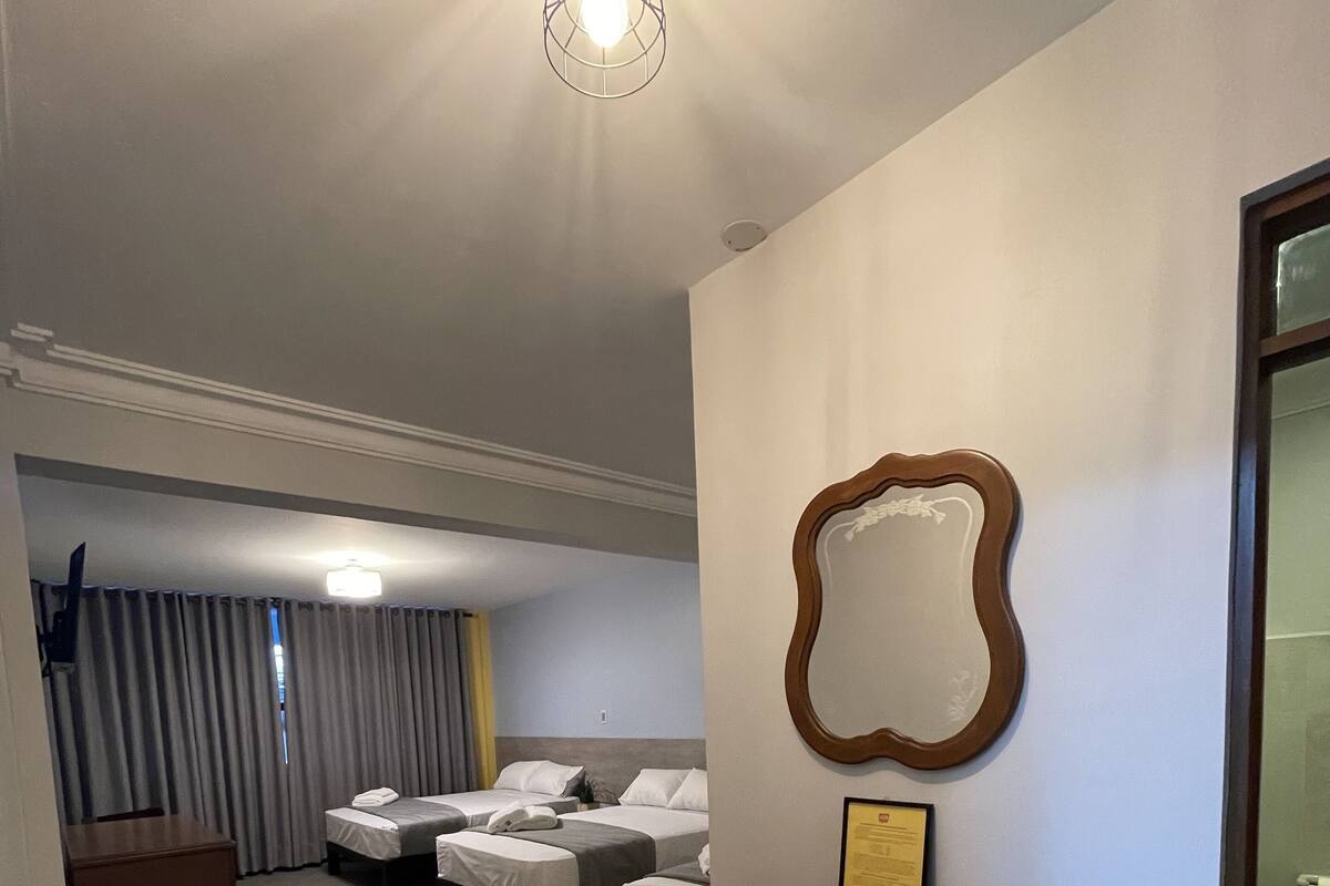 Habitación de hotel con cama, mesita de noche y espejo en la pared.