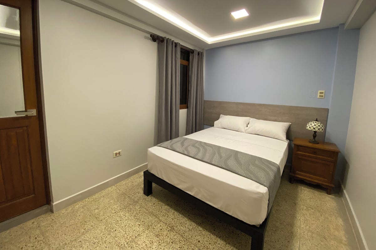 Un dormitorio con cama, mesita de noche y espejo.