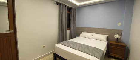 Un dormitorio con cama, mesita de noche y espejo.