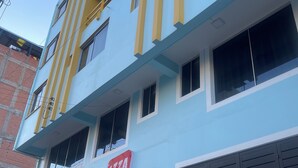 Ein mehrstöckiges Gebäude mit hellblauer Fassade, einem roten Schild mit der Aufschrift 'IZZA HOTEL' und einer großen Garagenöffnung.