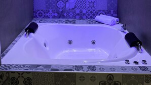 Ein modernes Badezimmer mit einer großen Badewanne, gemusterten Fliesen und einem Handtuch am Rand.