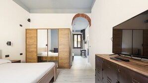A bedroom with a bed, wardrobe, TV, and a desk with a chair.
