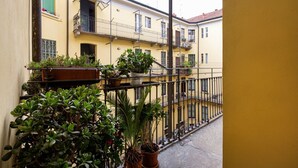 A yellow building with balconies, potted plants, and a metal railing.