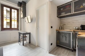 A compact kitchen with a window, a table with a chair, and a built-in stove.
