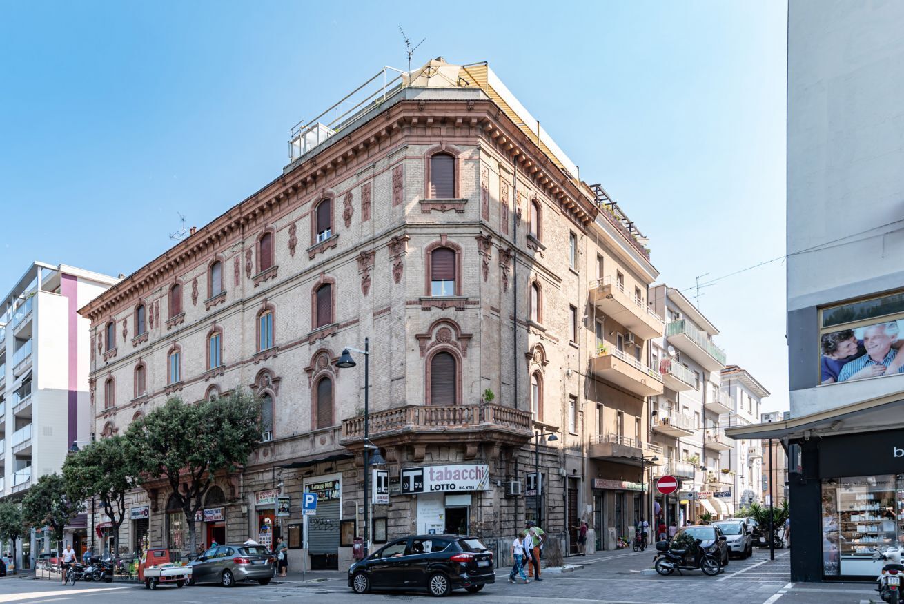 Ein historisches Gebäude mit Hauseingang in einer Ecke, ein Geschäft mit Schaufenster und ein freier Blick auf die Straße.
