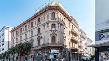 Ein historisches Gebäude mit Hauseingang in einer Ecke, ein Geschäft mit Schaufenster und ein freier Blick auf die Straße.