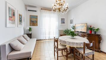 Un espace repas comprenant une table ronde, des chaises, un lustre et des œuvres d’art accrochées aux murs.