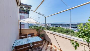 Ein Balkon mit Tisch und Stühlen, Blumentöpfen und Blick auf die Stadt.
