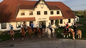 A building with the sign "Alte Schule" and a group of people on horses in front. - Apartment Vilm by Interhome (Dargun)