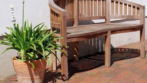 A wooden bench with a curved backrest and a slatted seat, positioned against a white wall. - Apartment Vilm by Interhome (Dargun)