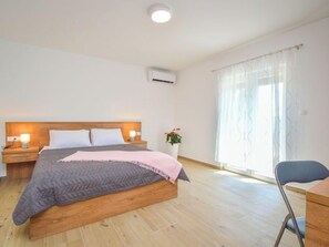Une chambre à coucher avec un lit en bois, des tables de chevet avec des lampes, une plante en pot et une fenêtre avec des rideaux.