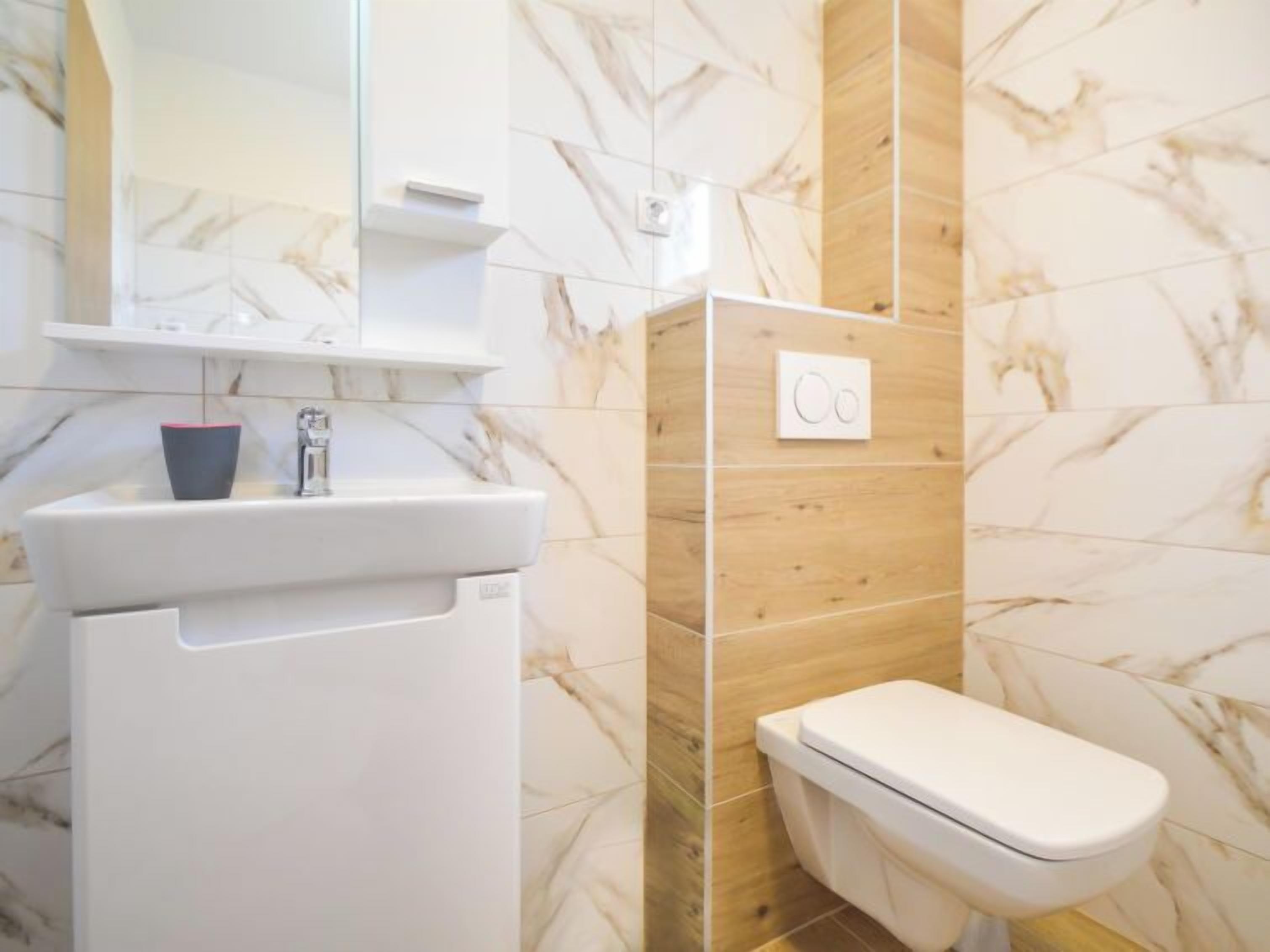 Un bagno con un lavandino bianco, uno specchio e un water.