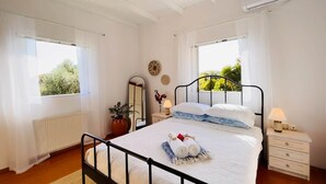 A bedroom with a bed, bedside tables, a mirror, a ceiling fan, and windows.