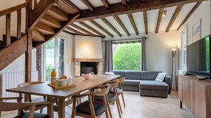 Una cocina moderna con una escalera de madera, un comedor con mesa y sillas, un sofá y un televisor.