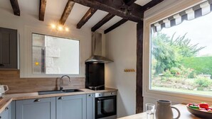 Una cocina moderna con gabinetes grises, un horno negro y una ventana con vista a un jardín.