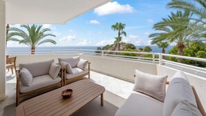 A balcony with a sofa and a table, overlooking a scenic view of the sea and palm trees. - Panorama by Interhome (Altea)