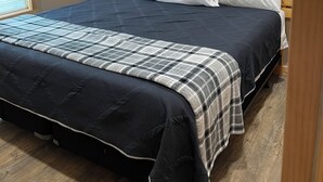 Un dormitorio con cama, ventilador de techo, un cuadro y ventana.