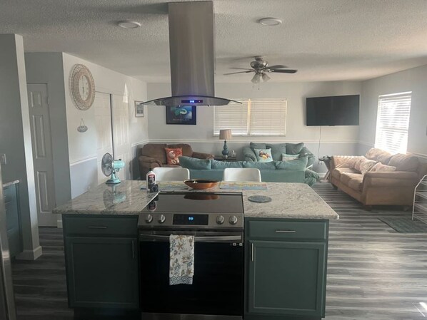 A modern kitchen with a central island, built-in oven, and stainless steel range hood.