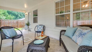 A covered patio area with wicker furniture, a table with a bottle, and a view of a wooden fence. - Atlanta Getaway w/ Private Yard: Near Airport (Atlanta)