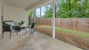 A covered patio with a sofa and chairs, a small table, and a wooden fence in the background. - Atlanta Getaway w/ Private Yard: Near Airport (Atlanta)