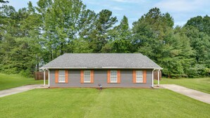 A single-story house with a grey brick exterior, orange shutters, and a well-maintained lawn. - Atlanta Getaway w/ Private Yard: Near Airport (Atlanta)