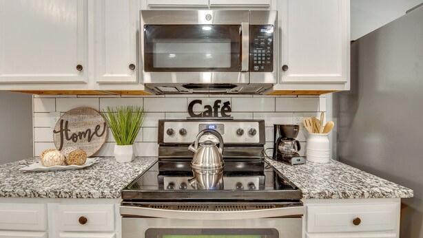 A kitchen with white cabinets, a stainless steel microwave, a stove, and a coffee maker. - Atlanta Getaway w/ Private Yard: Near Airport (Atlanta)