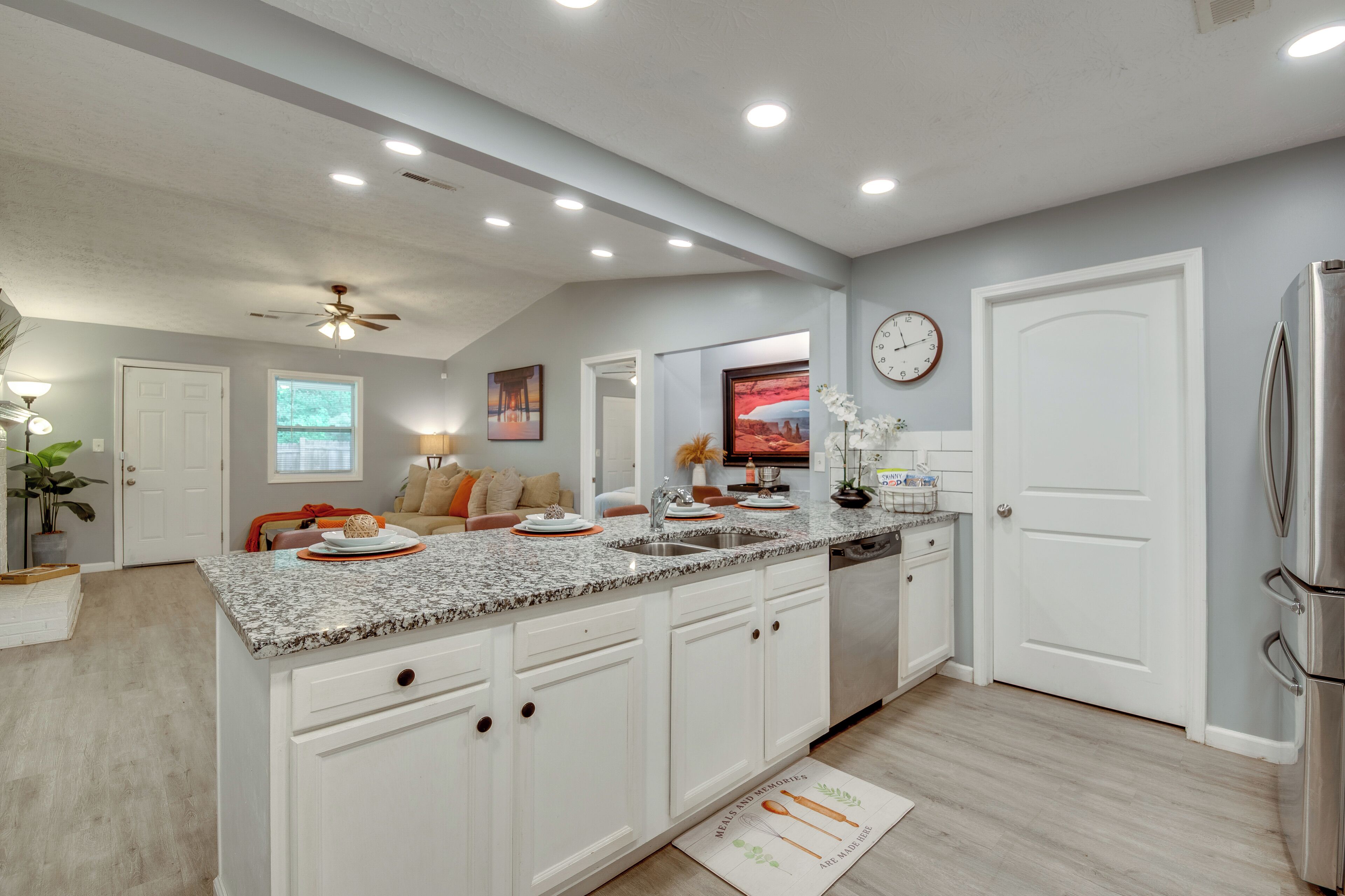A modern kitchen with white cabinetry, granite countertops, and stainless steel appliances.