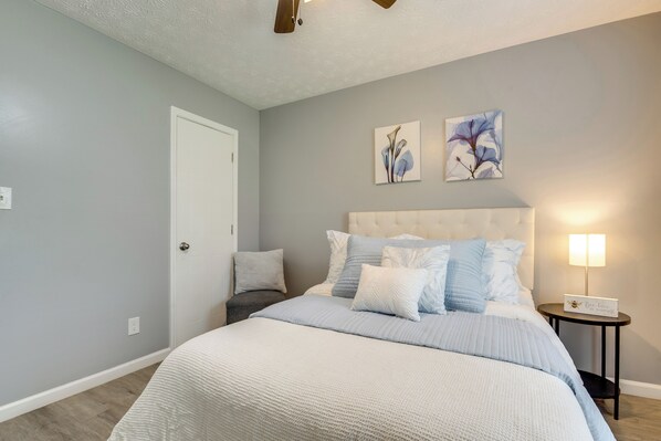 A bedroom with a bed, a nightstand, a lamp, and two wall art pieces.