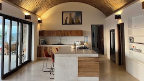 Een moderne keuken met een visgraatplafond, houten keukenkasten, een centraal eiland en een groot raam met uitzicht op een mooi landschap.