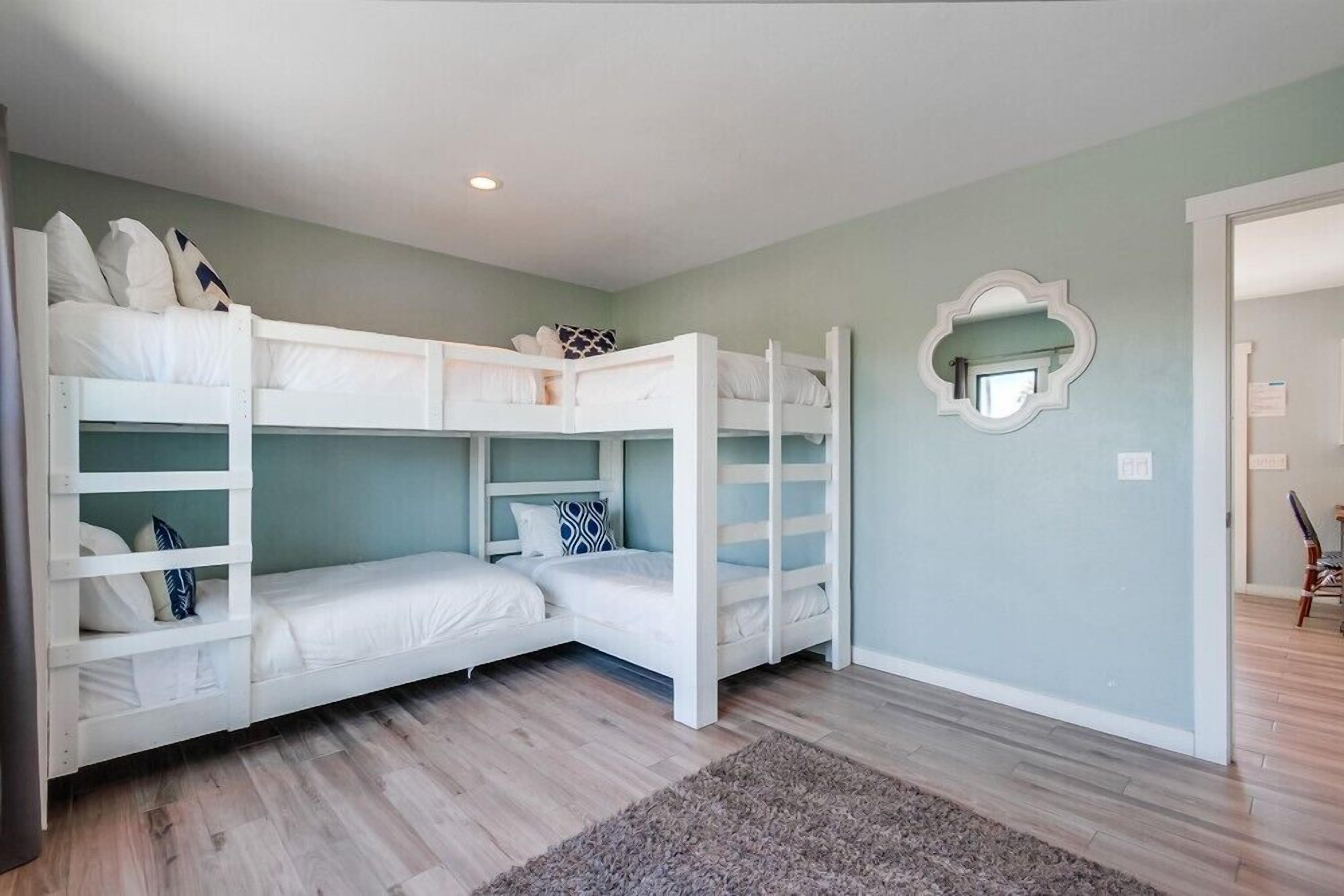 Une chambre avec des lits superposés, un miroir et un plancher en bois.