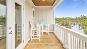 Une terrasse en bois avec des rampes blanches, deux chaises et une table.