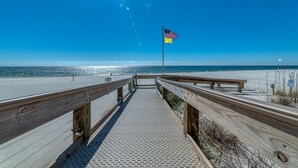 Una pasarela de madera que lleva a una playa con una bandera.