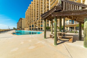 A pool area with a wooden deck, lounge chairs, and a wooden pergola. - Ground-Floor Beachfront 1BR + Bunk Alcove @ Phoenix V • Sleeps 6 • Pool, Beach & Splash Pad (Orange Beach)