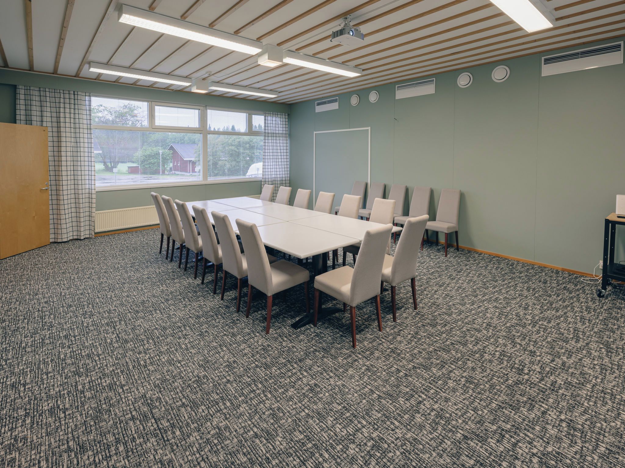 A conference room with a large table, chairs, and a projector.