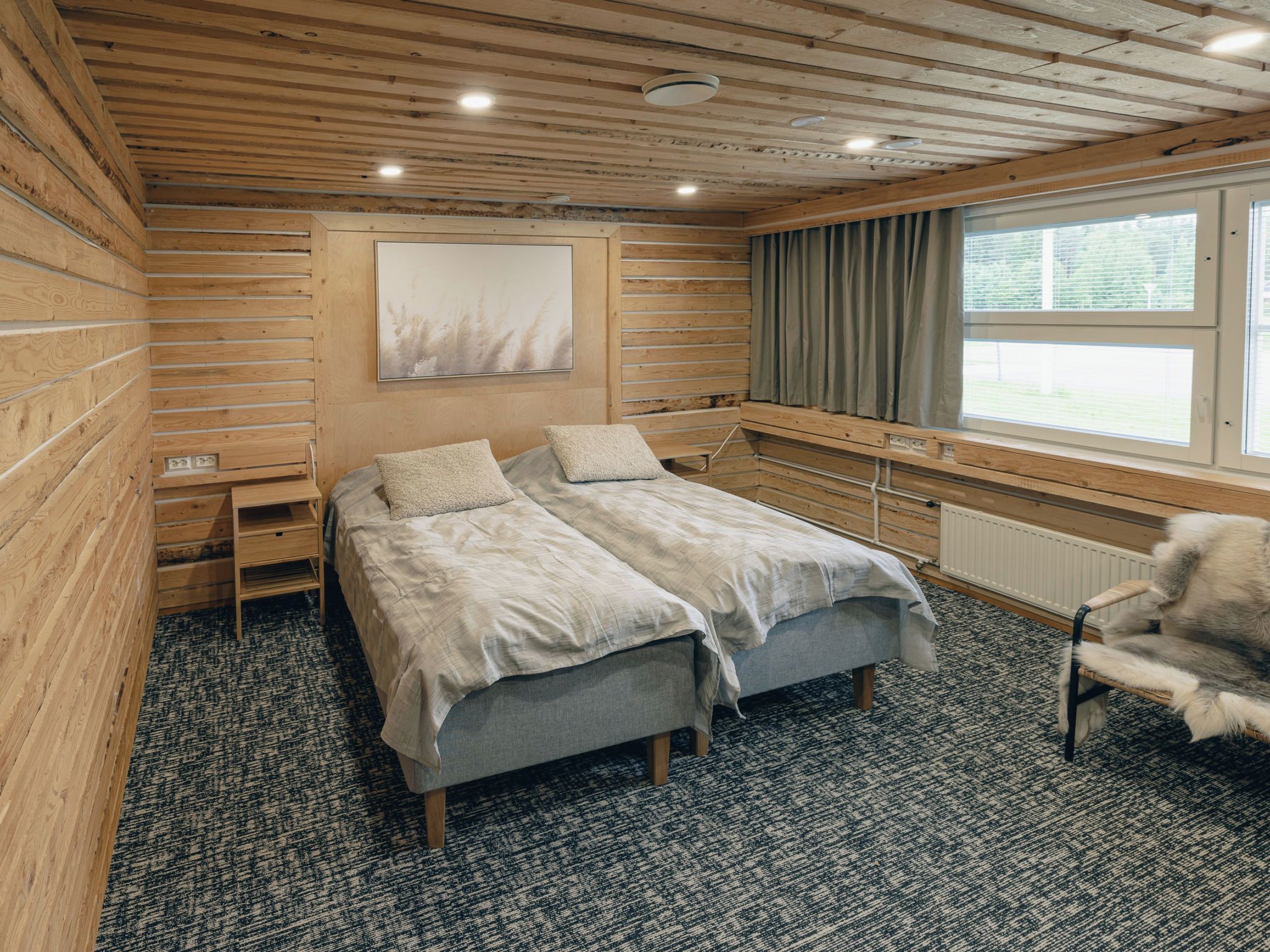 Un dormitorio con una cama doble, una silla, una ventana con cortinas y un radiador.
