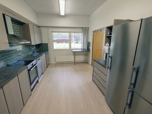 A modern kitchen with stainless steel appliances, a window with a view, and light wood flooring.